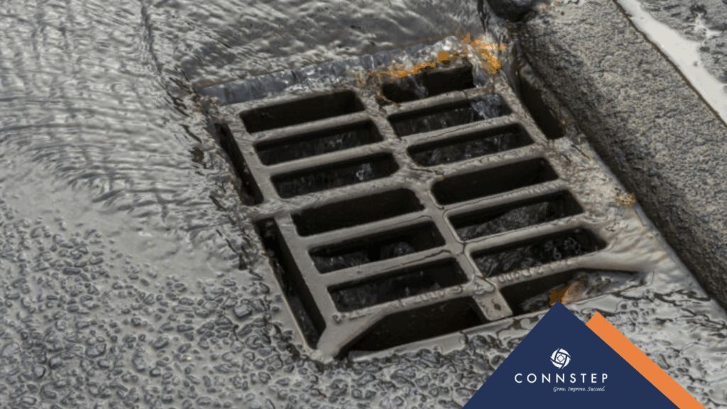 Water flows into a metal drain on a dark surface, logo in the corner.