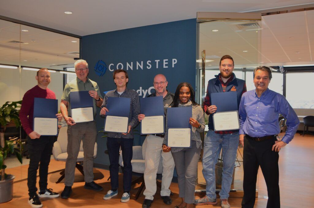 Seven people stand in front of a blue 