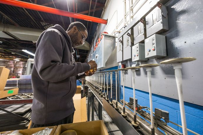 Person in a grey hoodie working at a factory station with machinery and boxes symbolizing  Developing Your People & Culture.
