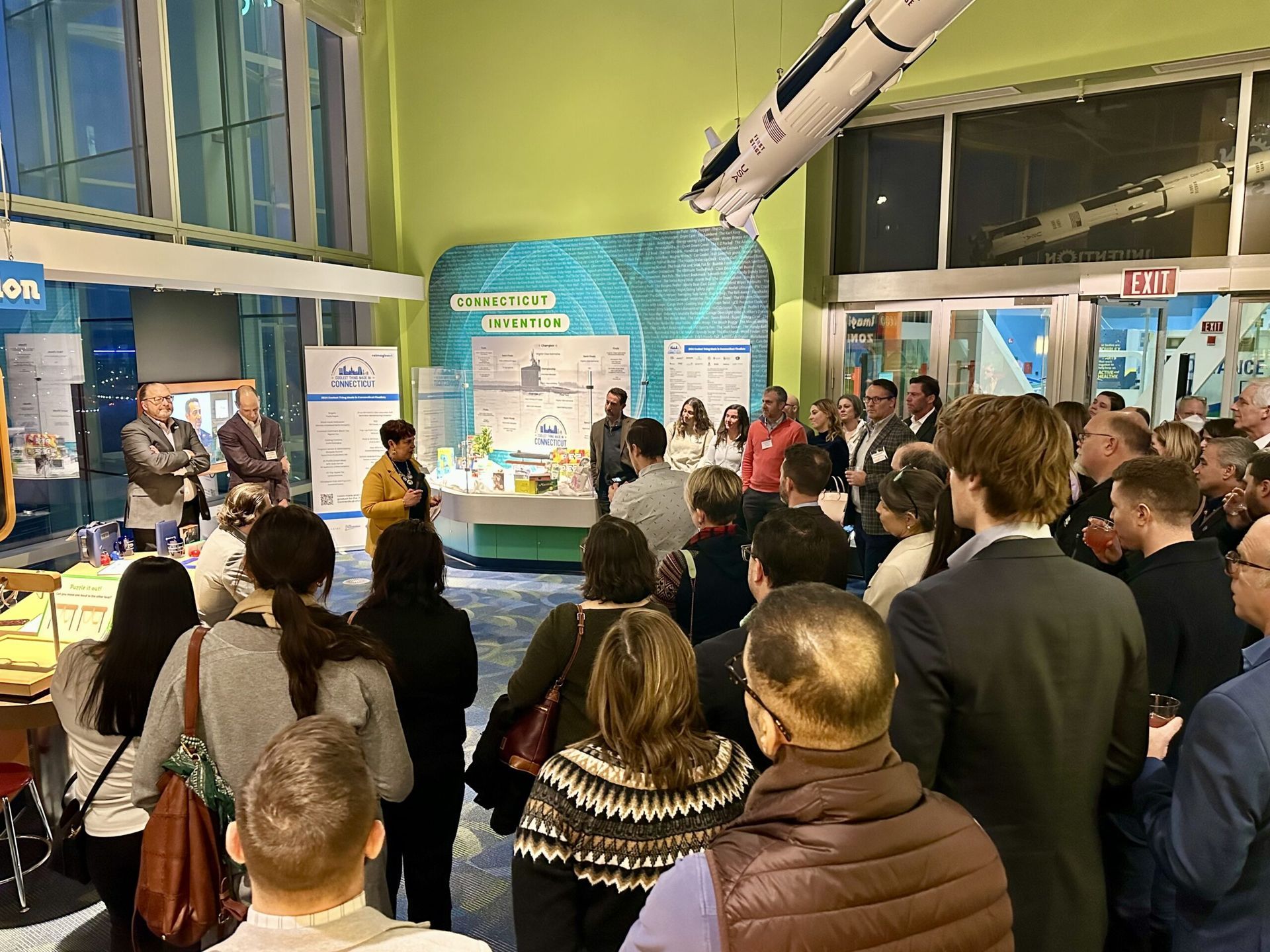 Group of people attending an event in a venue. A speaker is addressing the crowd.
