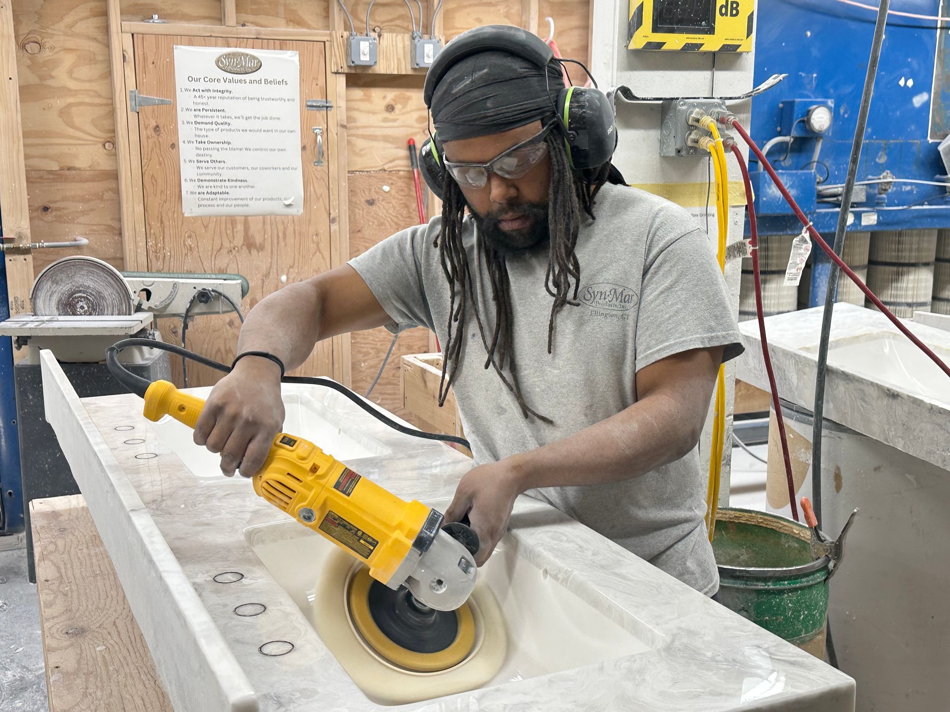 Person grinds a countertop with a power tool in a workshop.