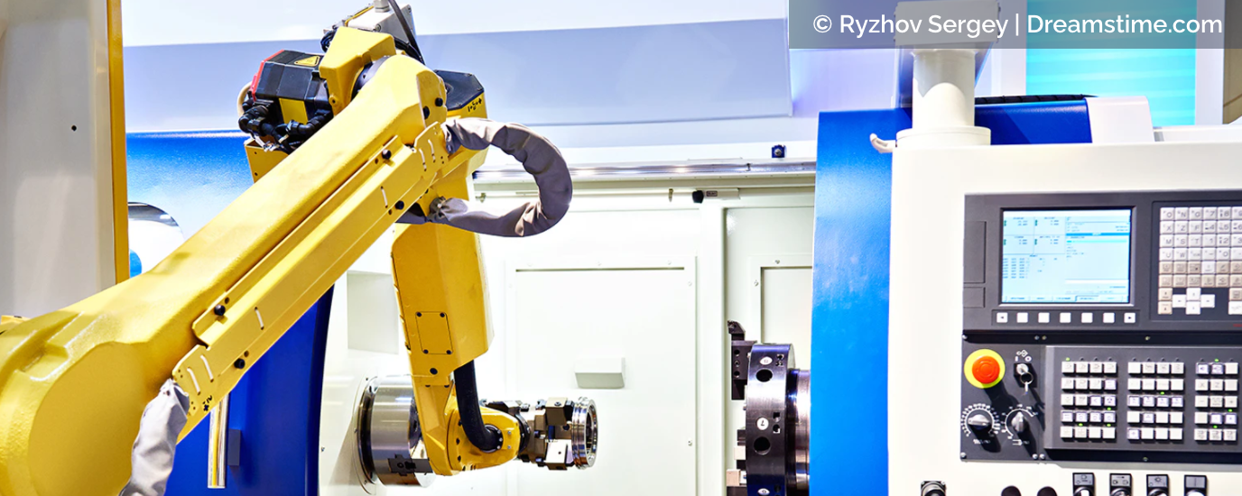 Yellow robotic arm operating near a machine with a control panel in an industrial setting.