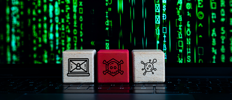 Three wooden blocks with cyber security symbols on a laptop keyboard with green code in the background.