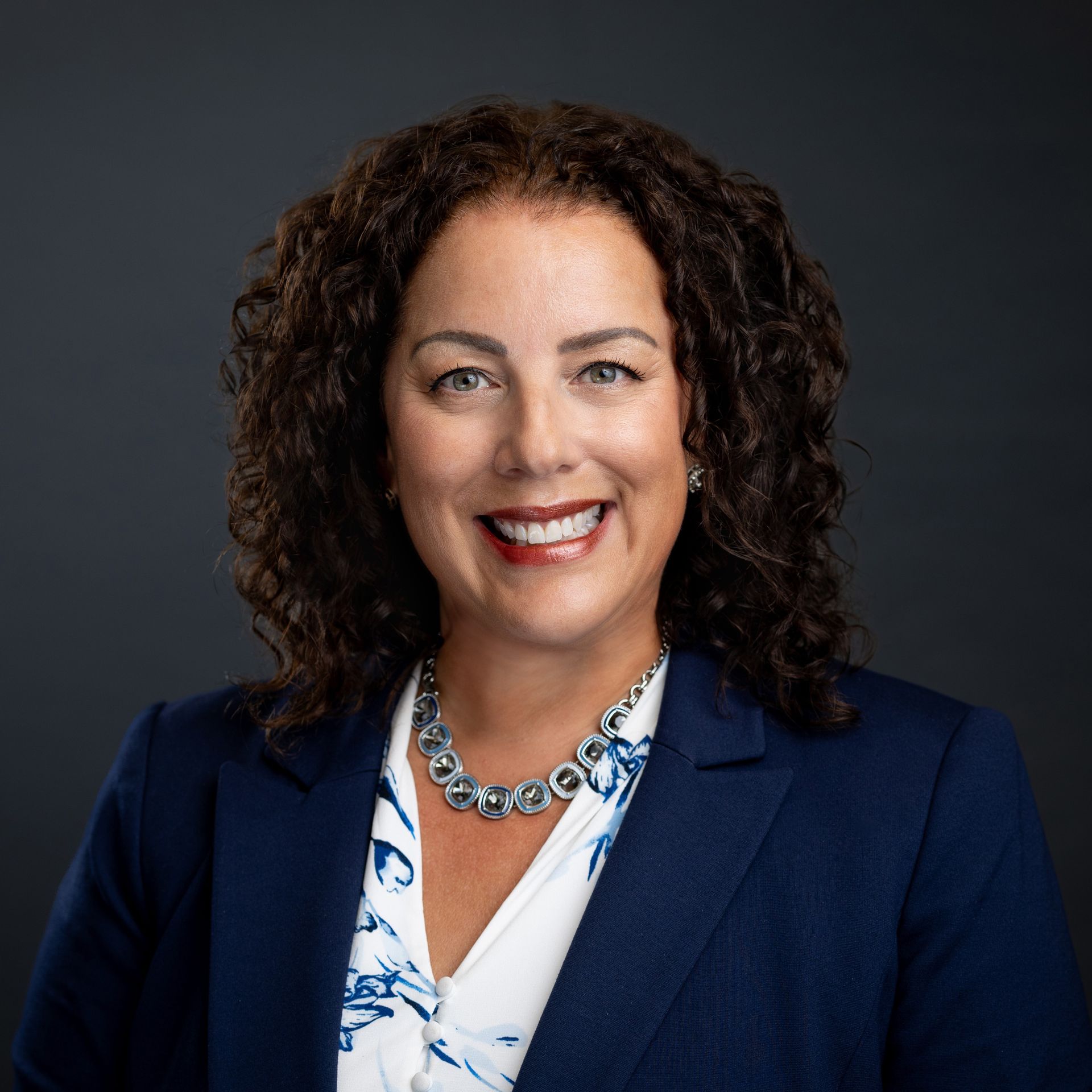 A woman with curly hair is smiling for the camera