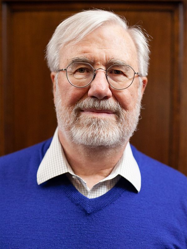 A man with glasses and a beard is wearing a blue sweater