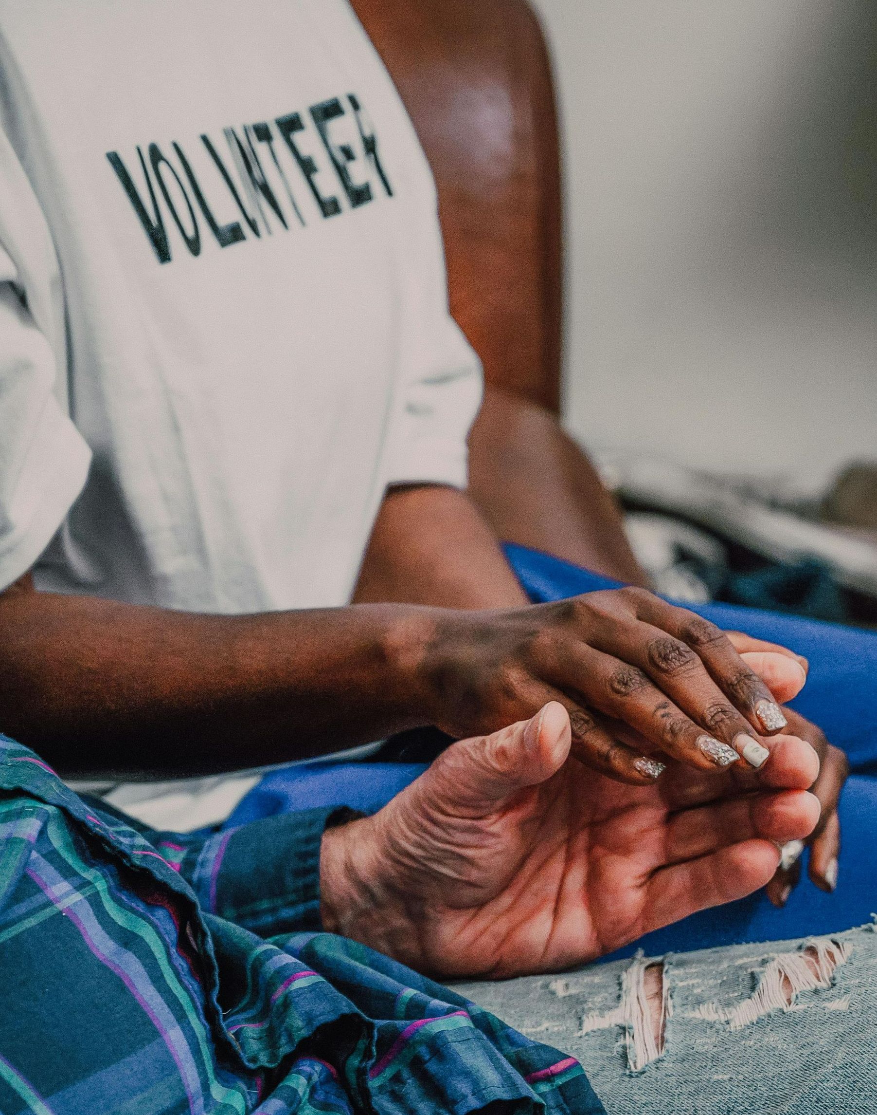 A person wearing a volunteer shirt is holding another person 's hand.