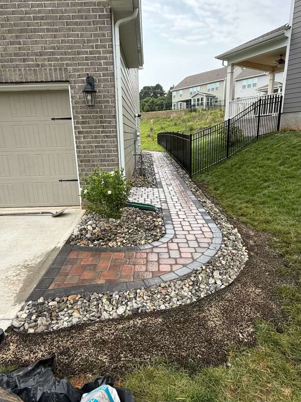 A brick walkway leading to a garage next to a house.