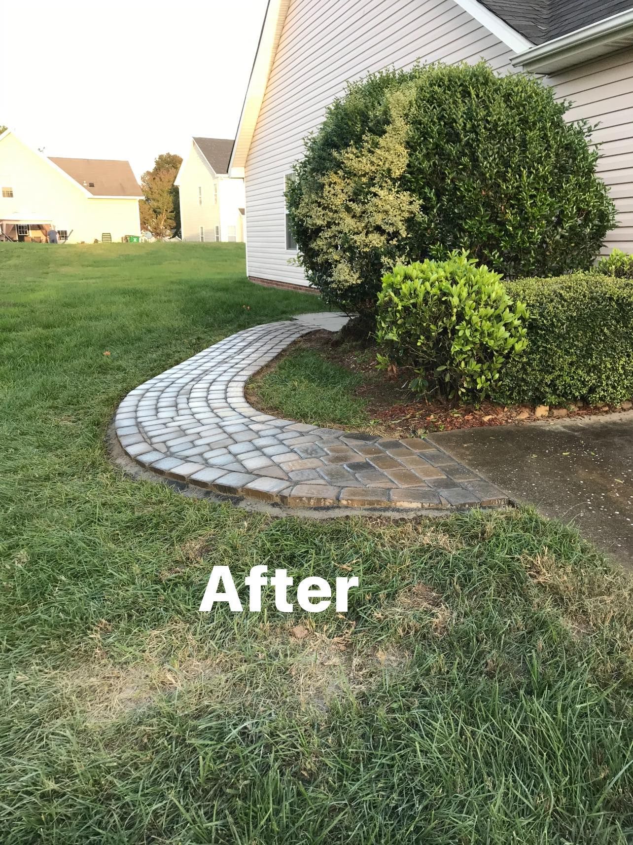A stone walkway leading to a house in a yard.