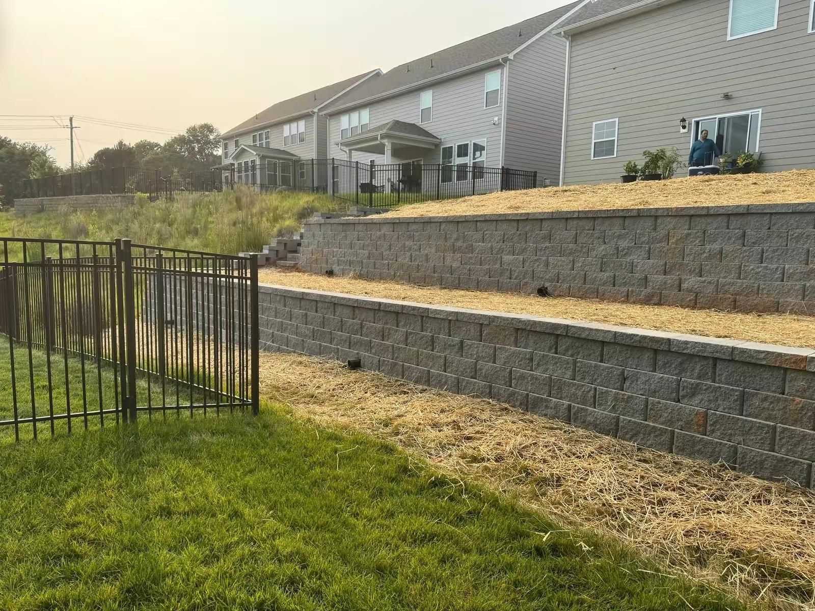 A brick wall with a fence in front of a house.