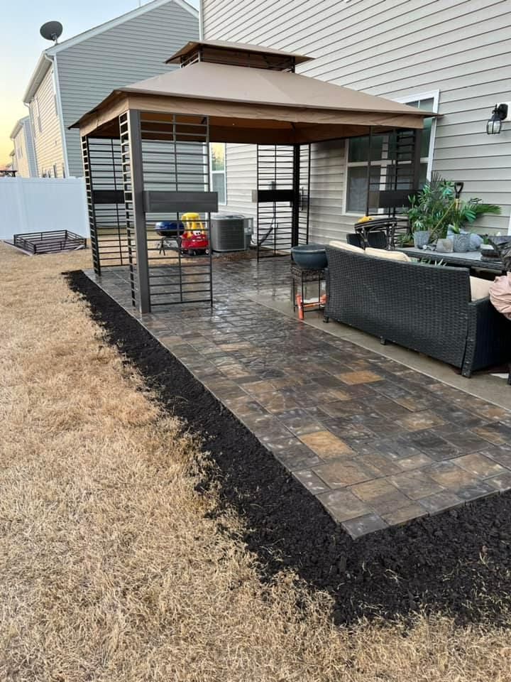 A gazebo is sitting on top of a patio next to a house.