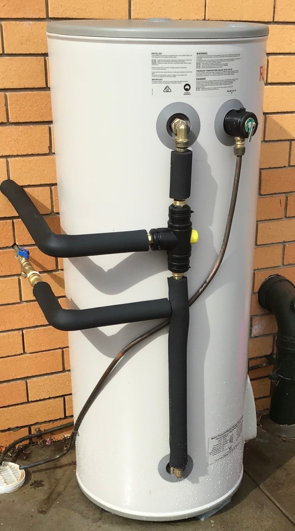 A water heater, pipes, and related equipment in a tiled utility room. A water heater, pipes, and related equipment in a tiled utility room.