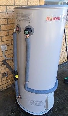 Rinnai water heater. Silver tank with insulated pipes, against a brick wall. Rinnai water heater. Silver tank with insulated pipes, against a brick wall.