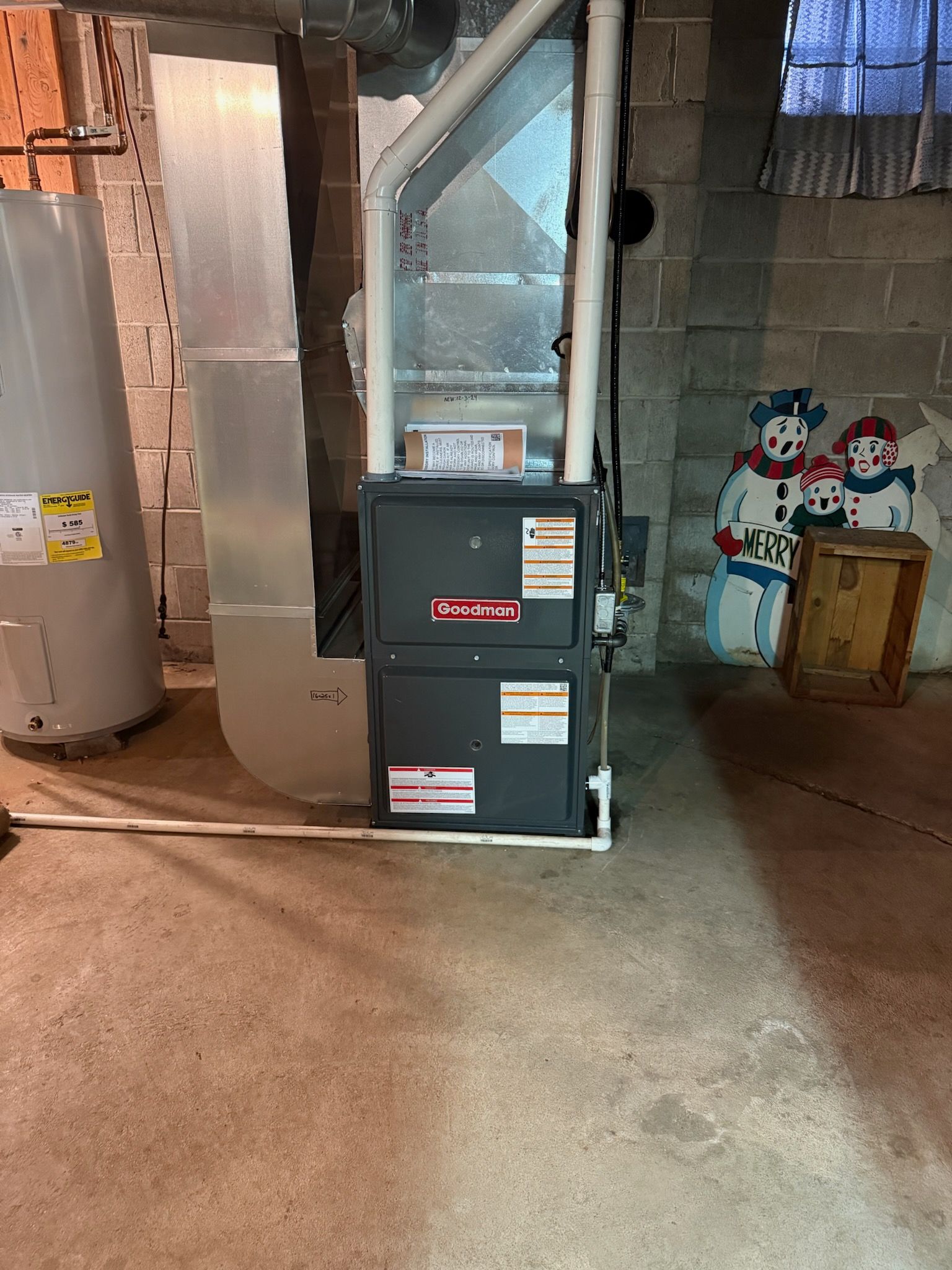 Furnace and water heater in a basement. Ductwork and cement walls. Decor on the right.