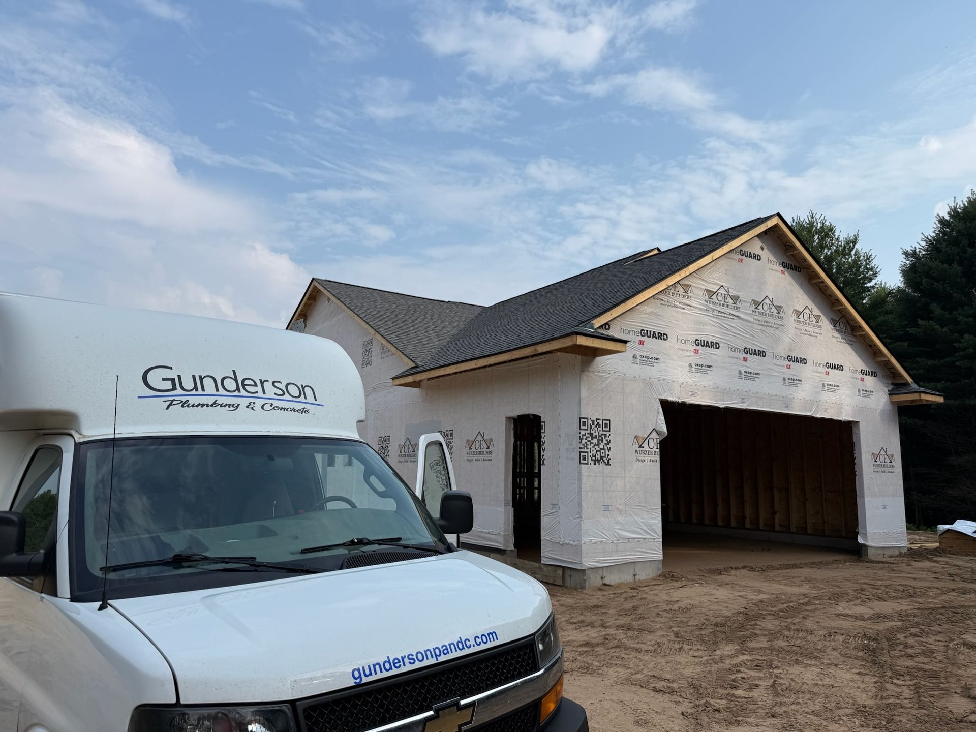 White van in front of a building under construction; white exterior, open garage, blue sky background.