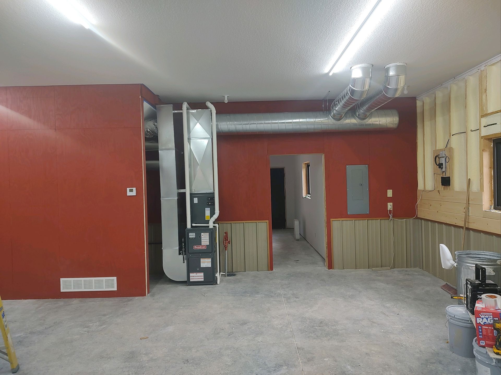 Interior view of room under construction with HVAC system and red walls.