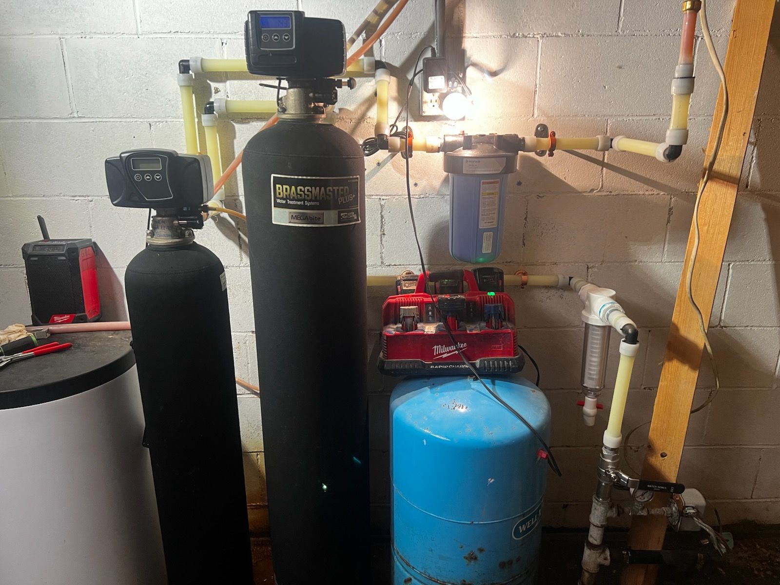 Water filtration system in a basement: black and blue tanks, yellow pipes, various digital control units.
