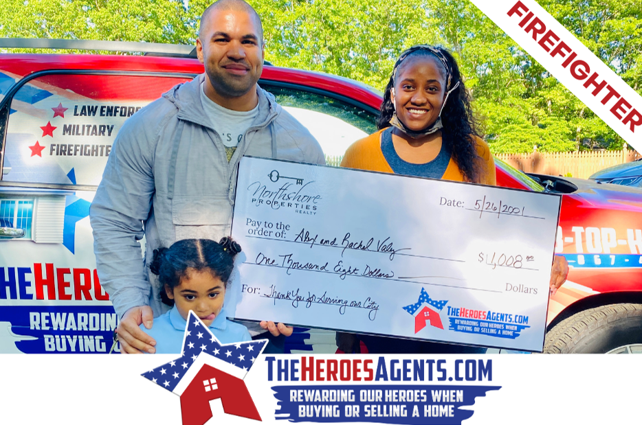 A man and woman are holding a large check in front of a firefighter truck.