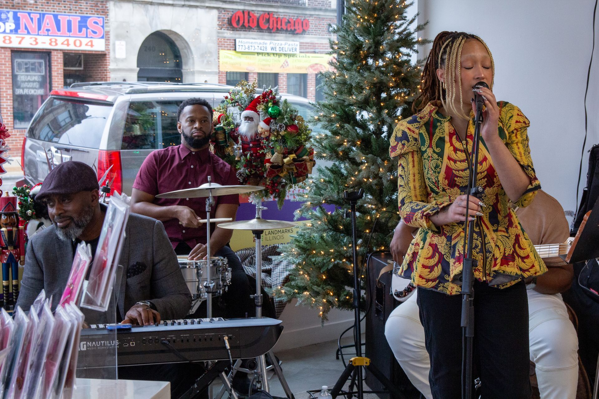 Singer, drummer, and keyboardist performing in storefront.