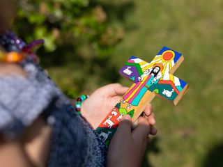 Hands holding a colorful cross-shaped craft against a blurred green background
