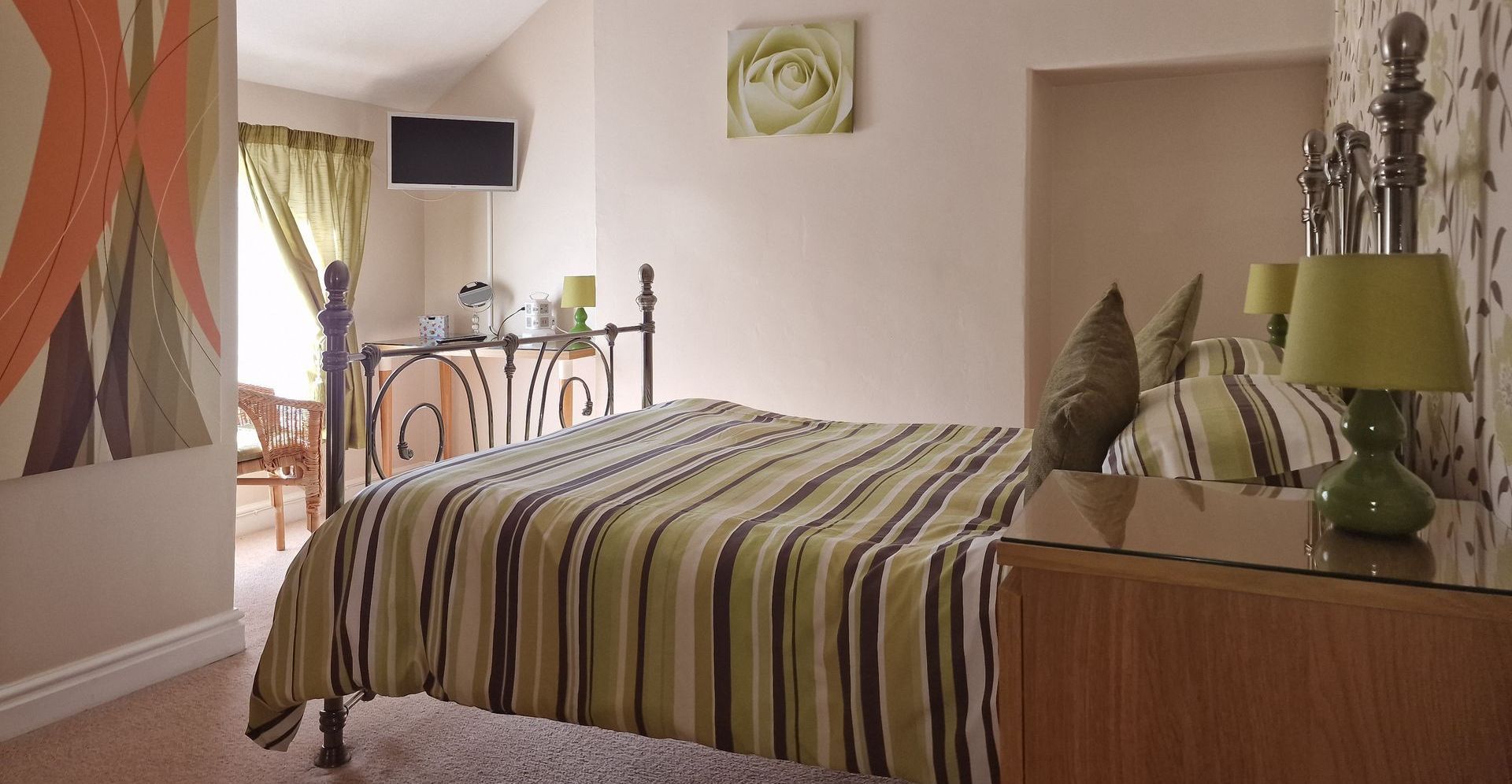A bedroom with a striped bed and lamps