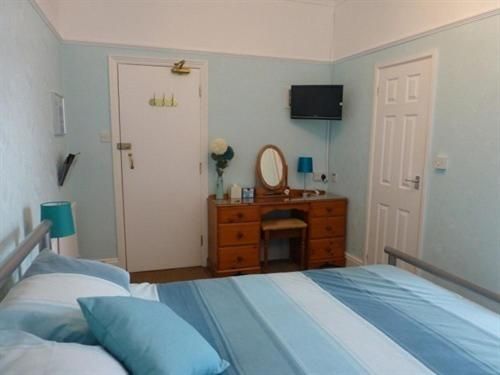A bedroom with a bed a desk and a television