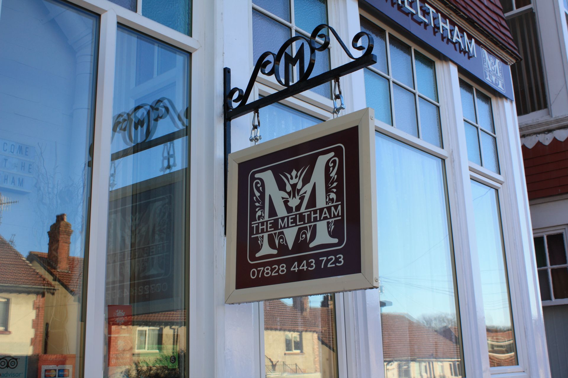 A sign for a guest house hangs over a busy street