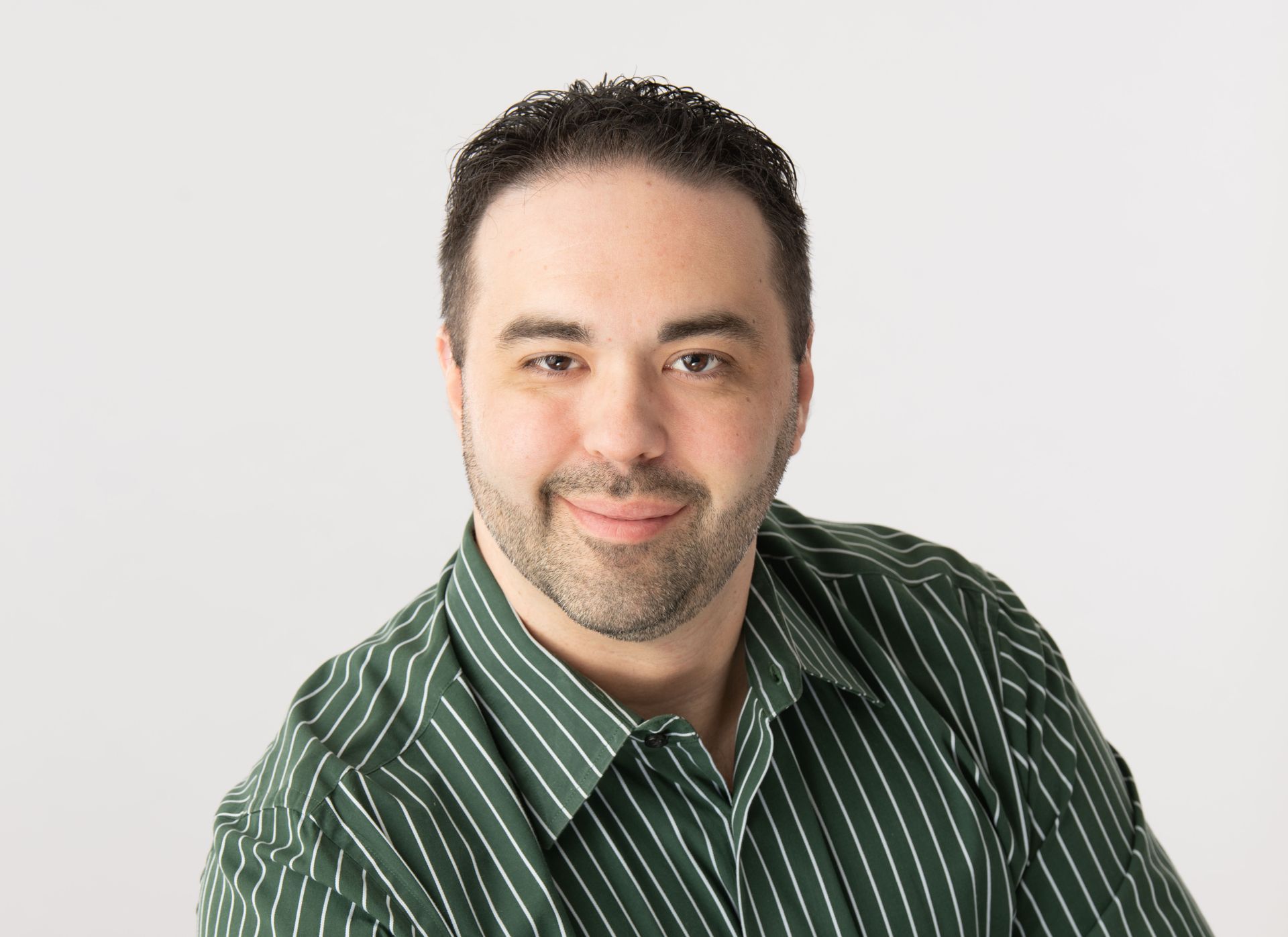 Man in a green striped shirt smiles against a white background.