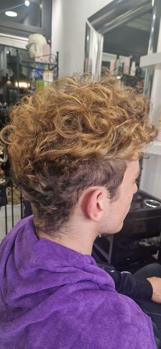 Un uomo con i capelli ricci si sta tagliando i capelli in un salone.