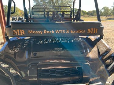 A black vehicle with a sign on the back that says mr messy rock wts & exotics