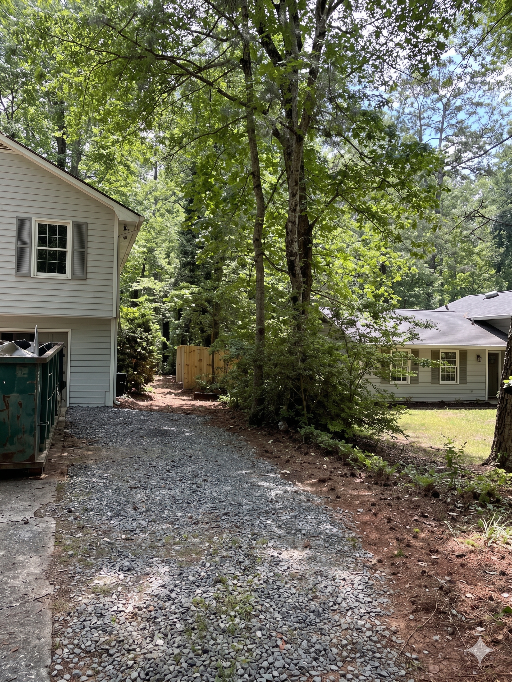 Wooden fence opening to a dirt path through a green wooded garden