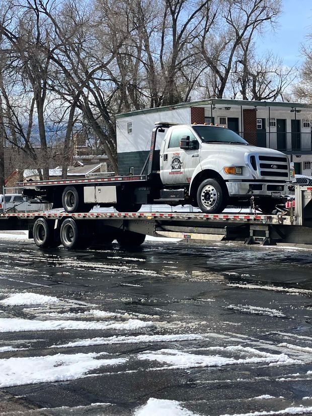 A tow truck is towing a truck on a flatbed trailer.