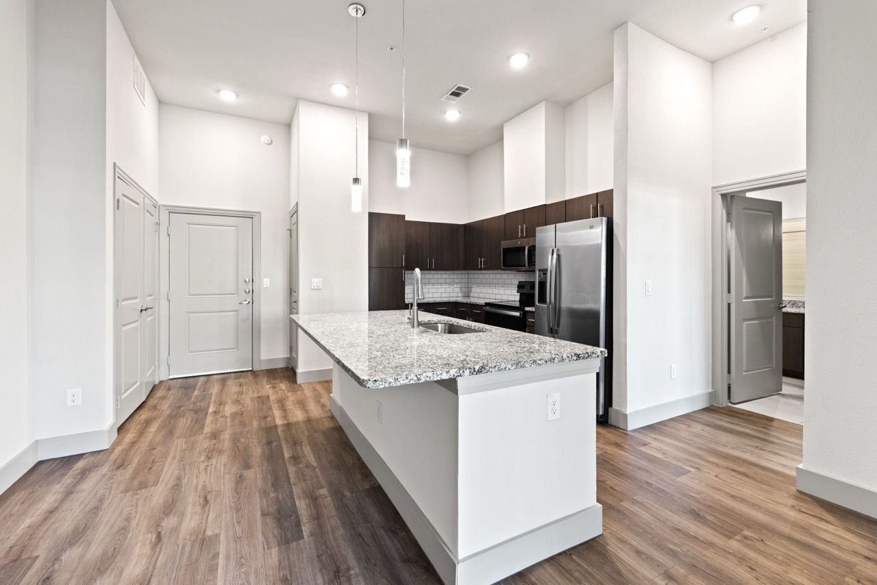 Open-concept kitchen with a large island, granite countertops, dark cabinets and stainless steel appliances.