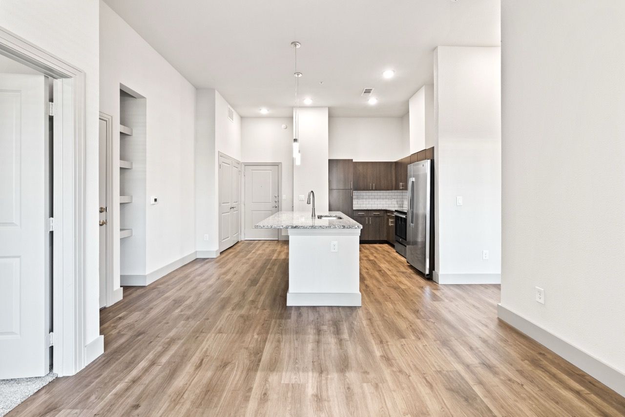 Open-concept kitchen with an island, granite countertops, and stainless-steel appliances in a bright apartment.