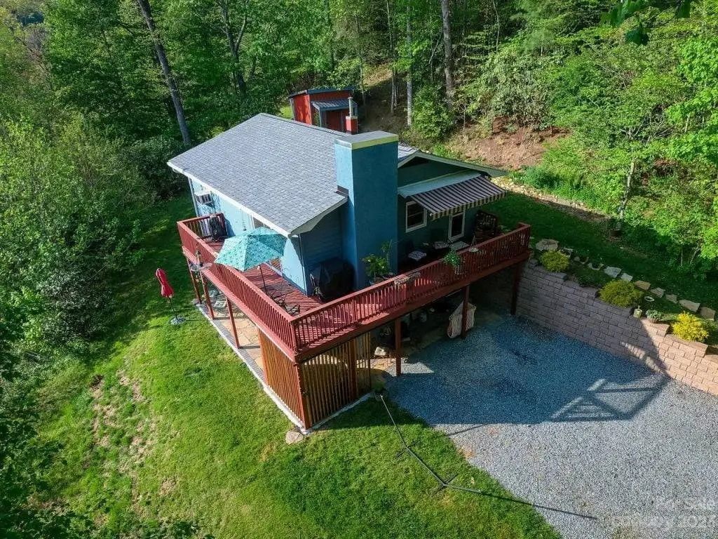 An aerial view of a house with a large deck surrounded by trees.
