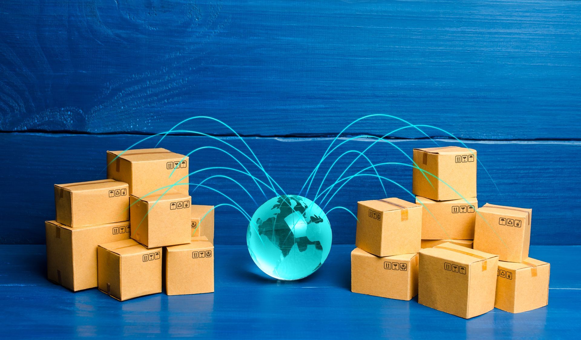 A stack of cardboard boxes and a globe on a blue wooden table.