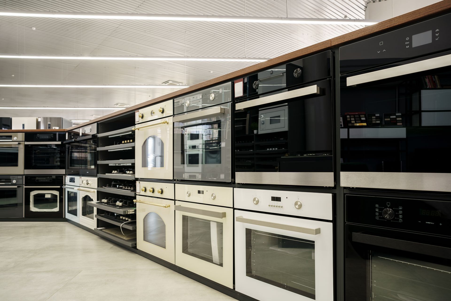 A row of ovens are lined up in a kitchen.