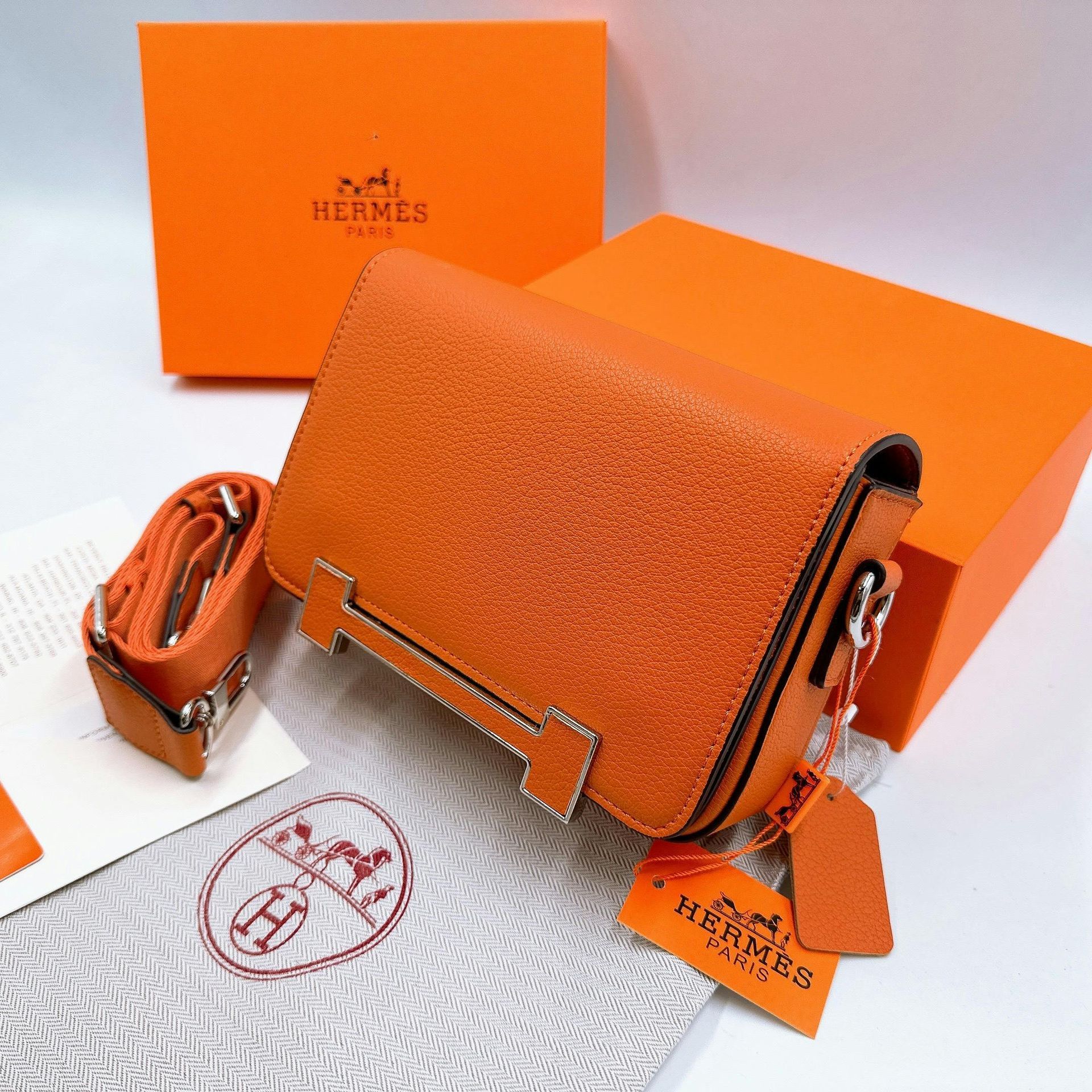 An orange hermes purse sits next to an orange box