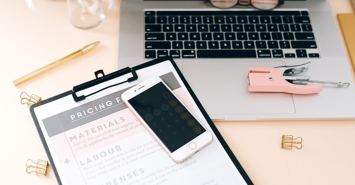 A clipboard with a cell phone on it next to a laptop.