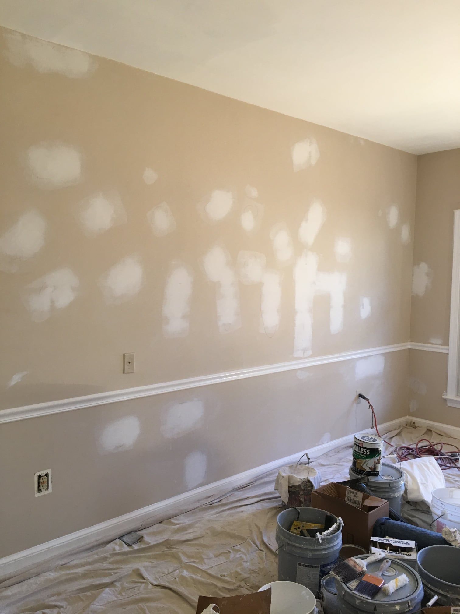 A room that is being painted with buckets of paint on the floor.