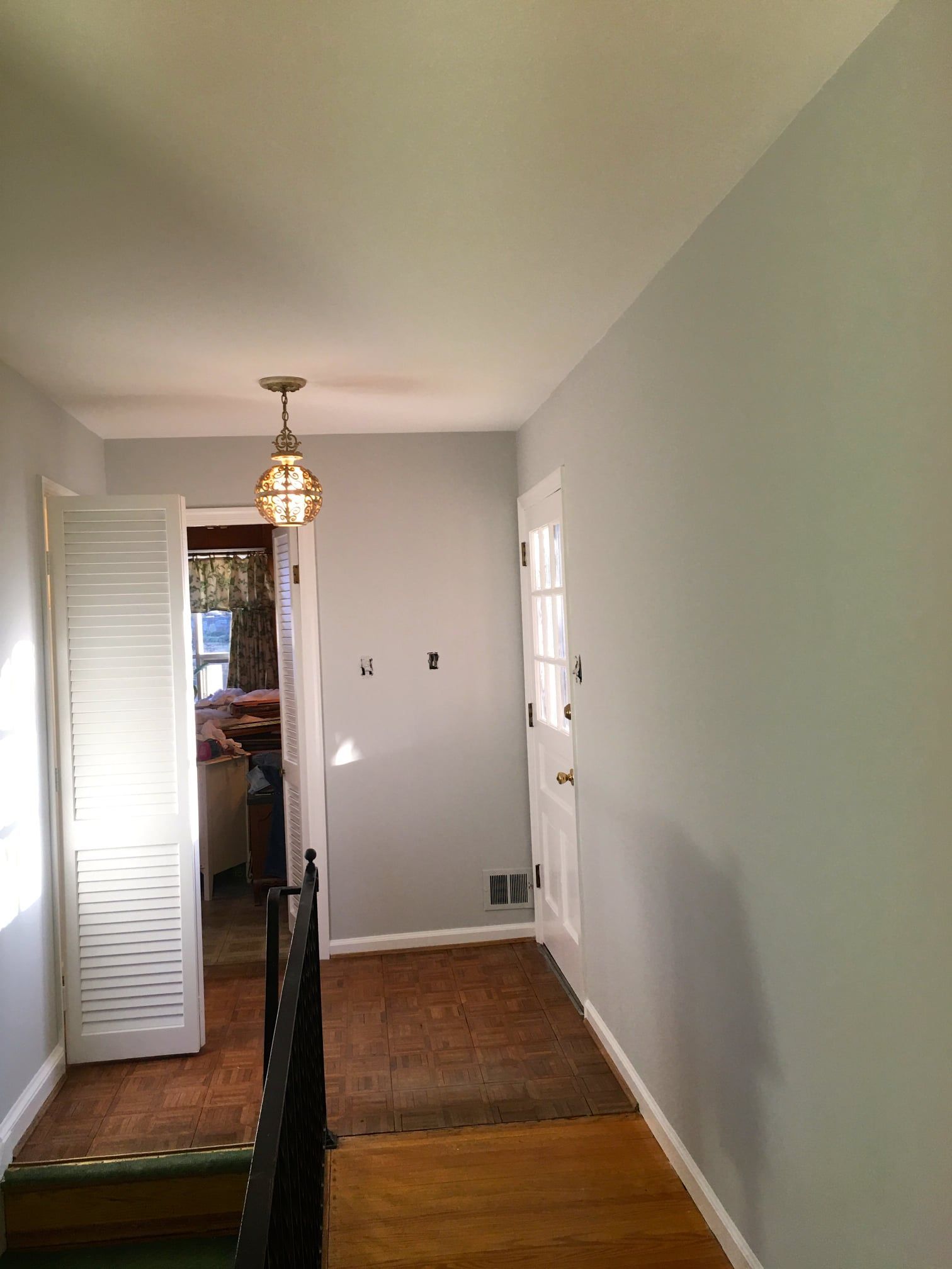 A hallway in a house with a light hanging from the ceiling.