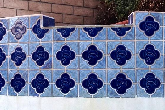 A brick wall with blue tiles with flowers on them