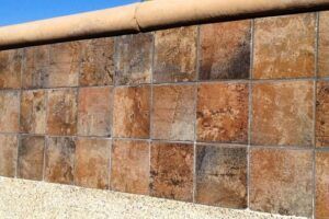 A close up of a tiled wall with a blue sky in the background.