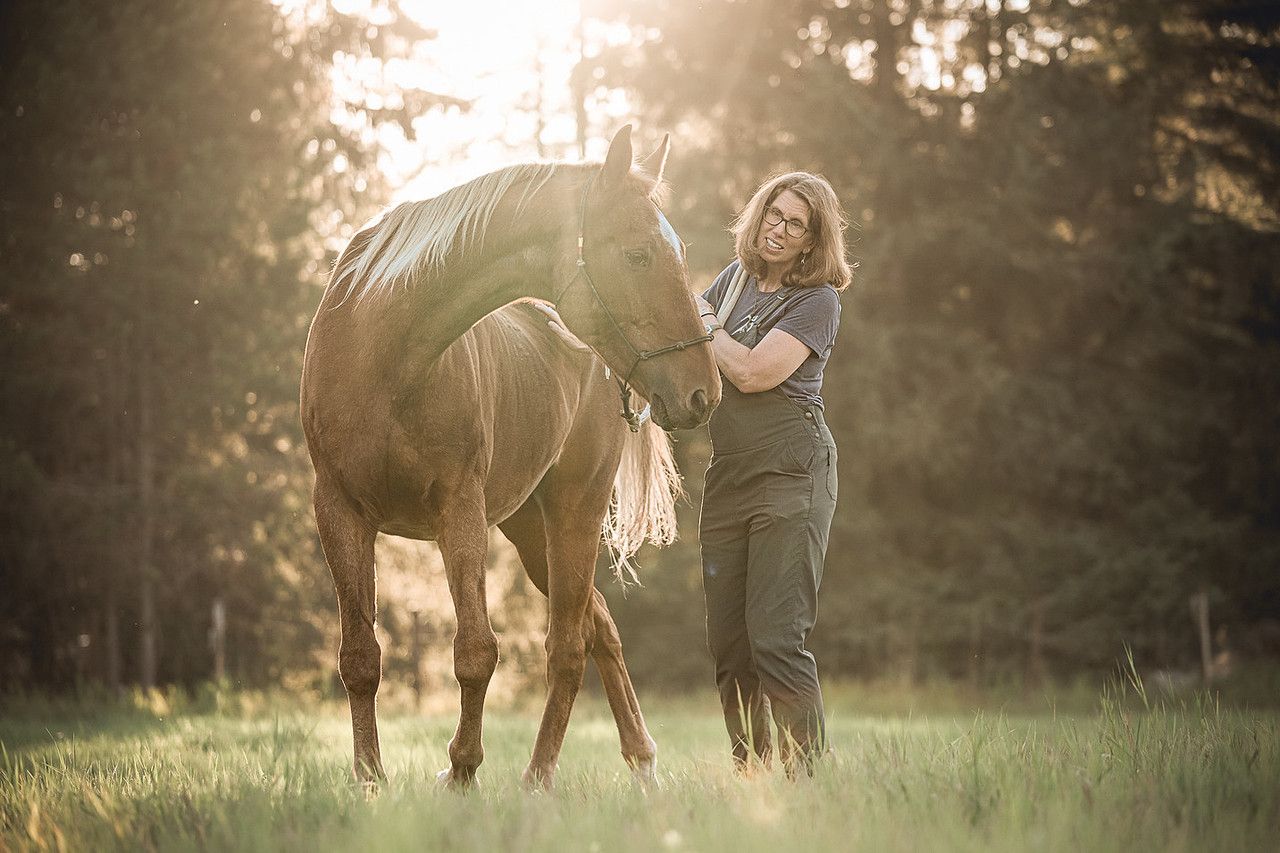 Hands gently cupping a small, fledgling bird with brown and yellow feathers outdoors.