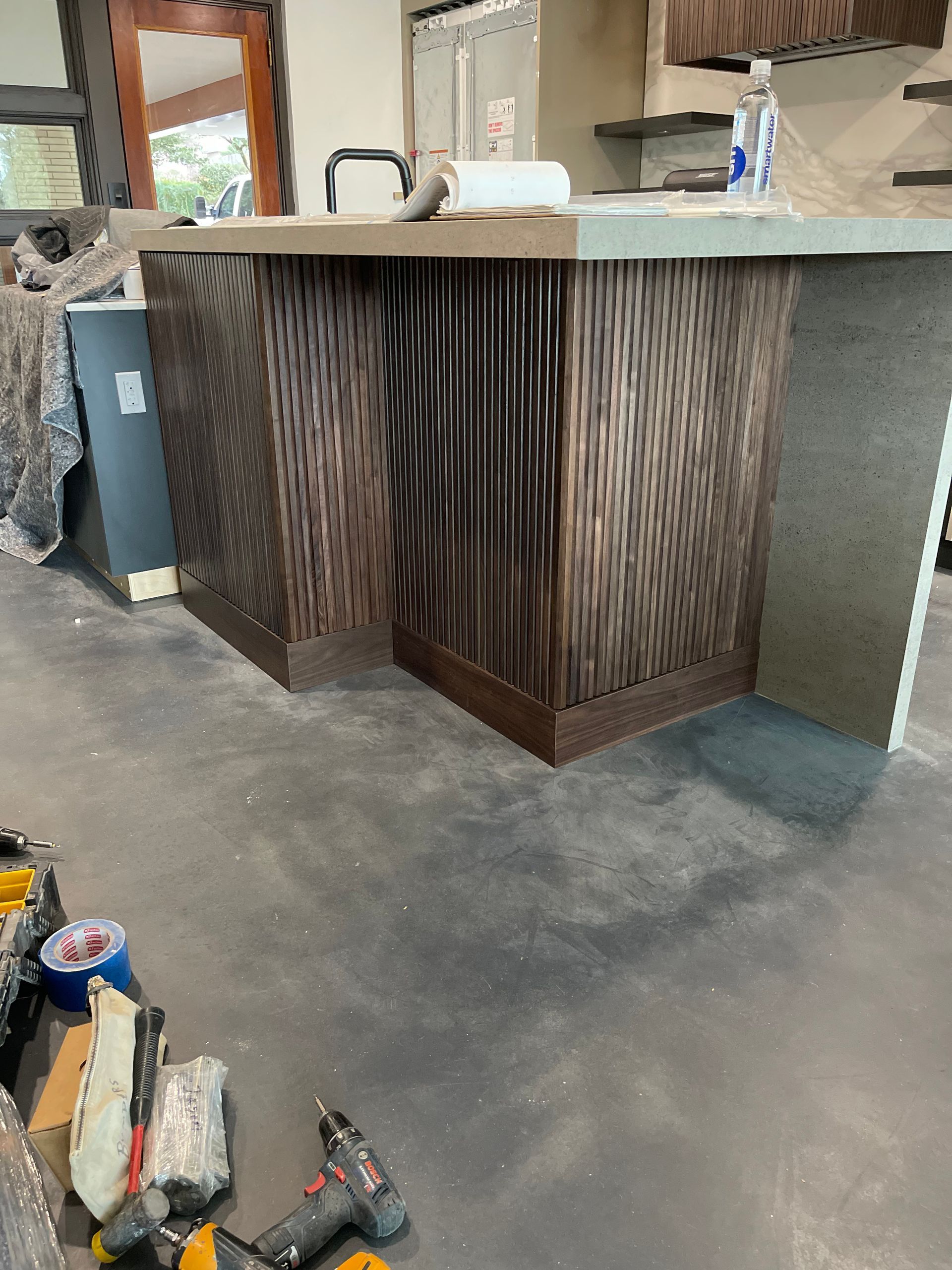 A kitchen with a bar and a lot of tools on the floor.