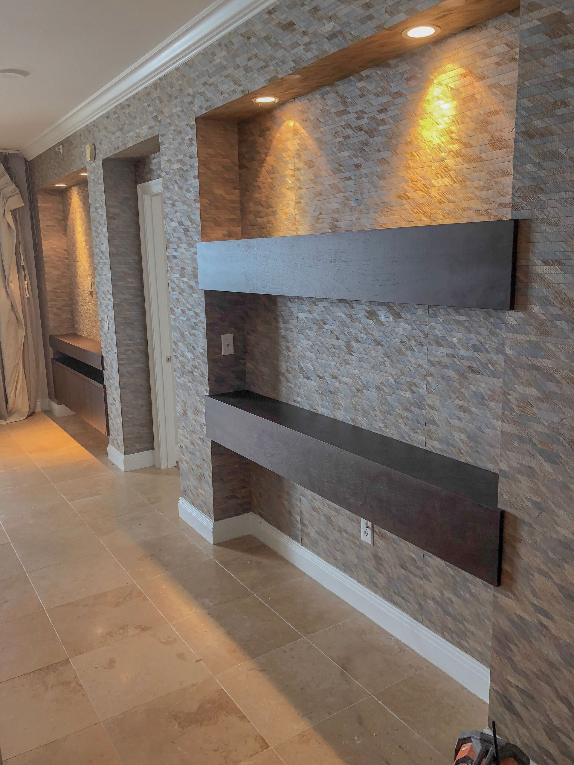 A kitchen with a marble counter top , black cabinets , and a hood.
