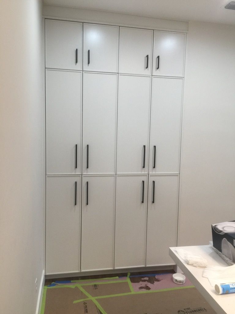 A room with a lot of white cabinets and a desk.