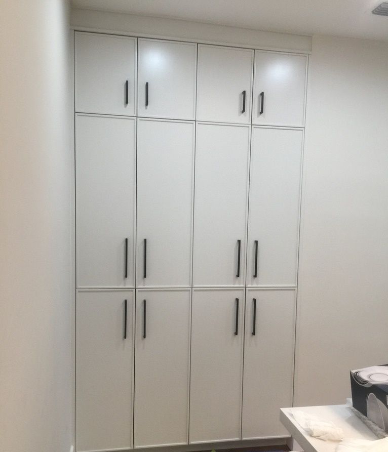 A kitchen with a sink and white cabinets with glass doors