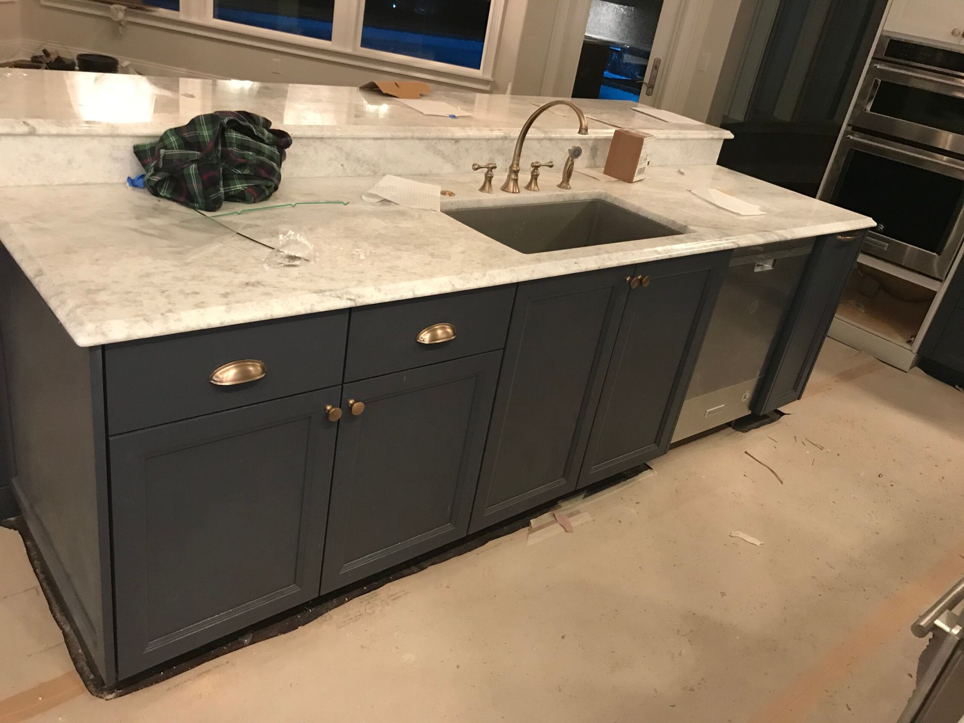 A kitchen with blue cabinets , a sink , and a dishwasher.