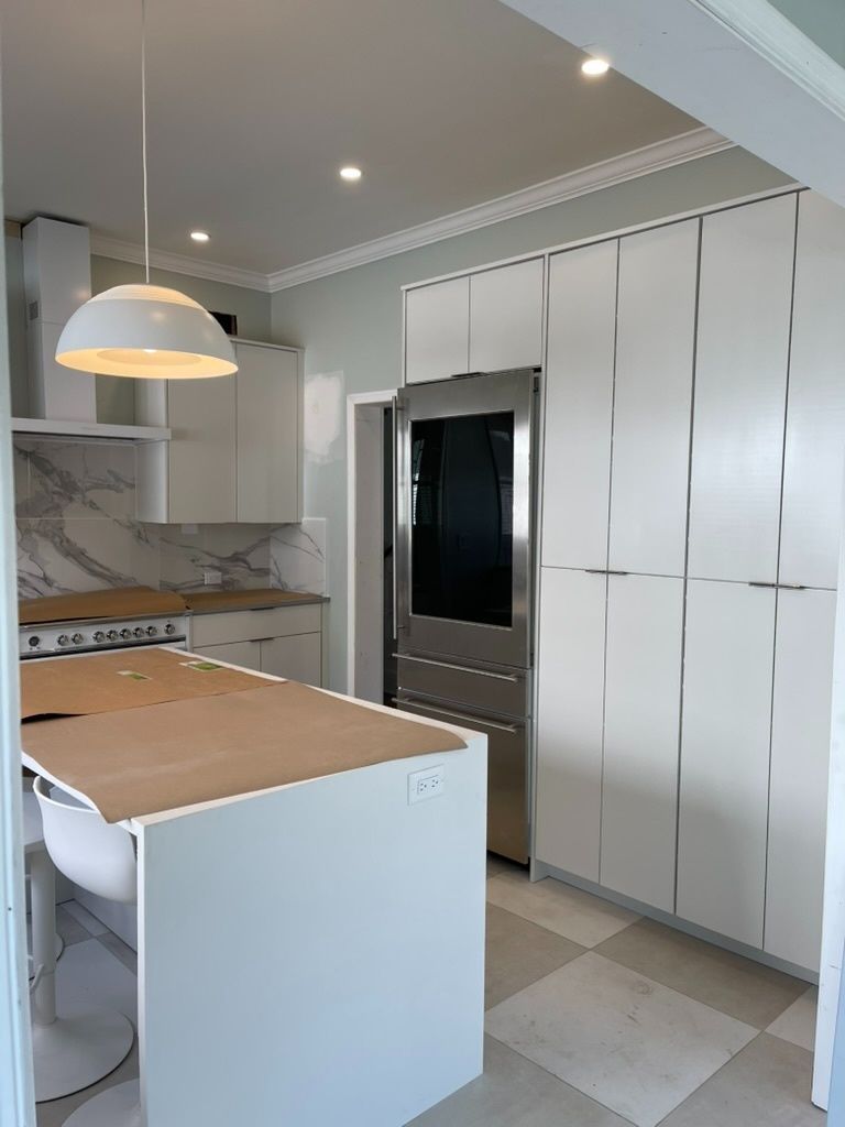 A kitchen with white cabinets , stainless steel appliances , and a large island.