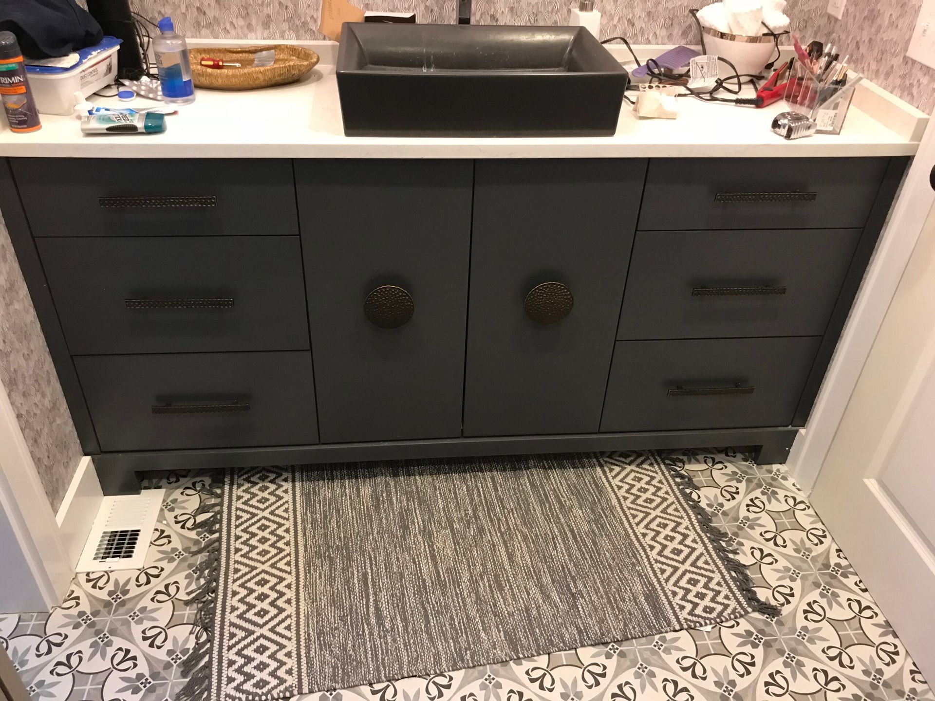 A bathroom vanity with a sink and drawers and a rug on the floor.